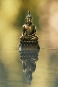 a buddha statue sitting on top of a body of water